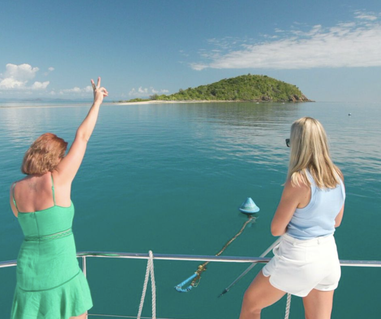 Guests waving at a Whitsunday island anchorage